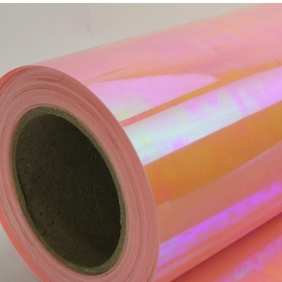 Rolo de plástico translúcido iridescente sobre superfície branca