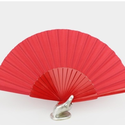Leque vermelho com armação em madeira e base metálica em forma de mão