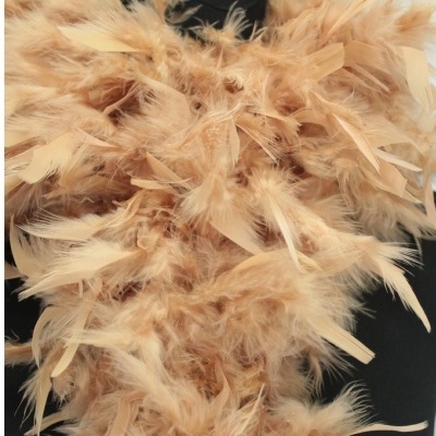 Acessório com penas bege claro sobre fundo escuro