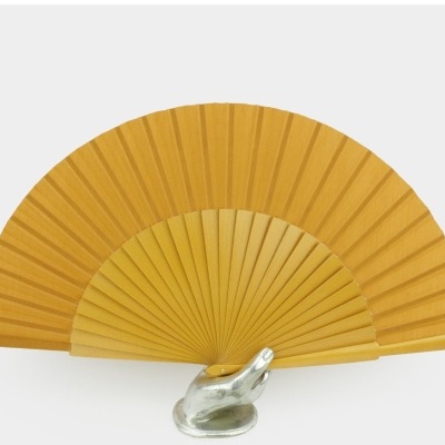 Leque amarelo tradicional em madeira exposto numa base metálica de mão