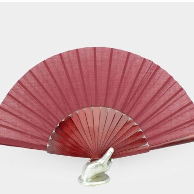 Leque vermelho em tecido com armação em madeira sobre suporte em forma de mão de vidro