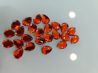 Gemas de vidro âmbar facetadas em forma de gota sobre superfície espelhada