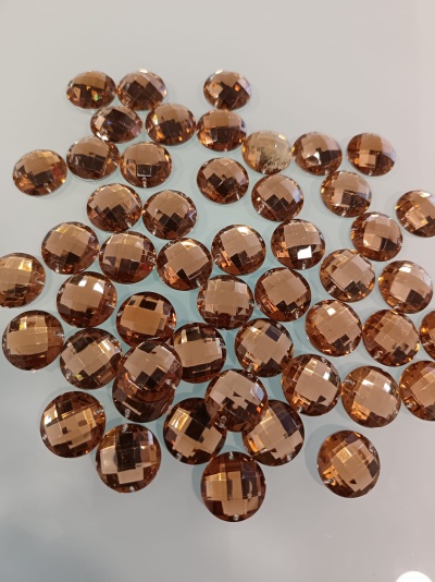 Pedras decorativas castanhas translúcidas facetadas redondas sobre superfície branca