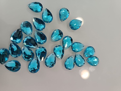 Cristais azuis em forma de gota facettados sobre superfície branca