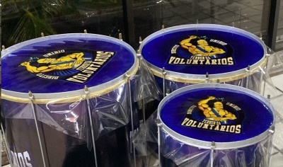 Três tambores azuis com logotipo 'FORÇA VOLUNTÁRIOS' e estrutura metálica, em ambiente interior