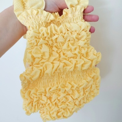 Roupa de bebé amarela com textura franzida e alças com bolinhas brancas