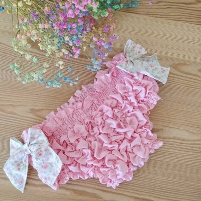 Cueca de bebé rosa com laços florais e flores coloridas ao lado