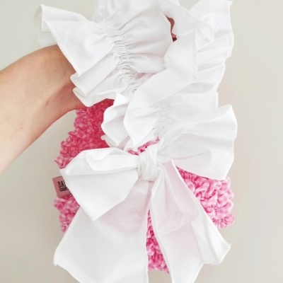 Dois scrunchies, um rosa frisado com etiqueta, outro branco com laços grandes