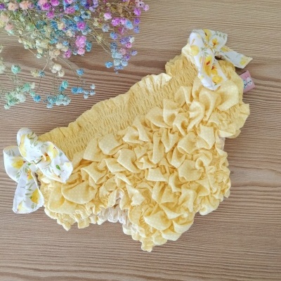 Cueca amarela com laços brancos em madeira clara com flores secas