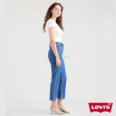 Calças de ganga azuis Levi's de corte reto usadas por mulher com t-shirt branca e sandálias de salto