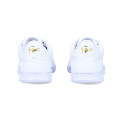 Sapatilhas brancas Lacoste vistas por trás com logótipo dourado de crocodilo.