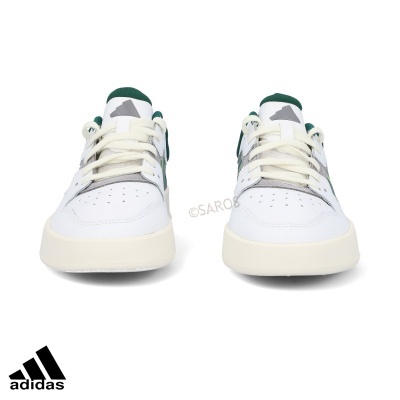 Ténis Adidas brancos com detalhes verdes e cinzentos sobre fundo branco