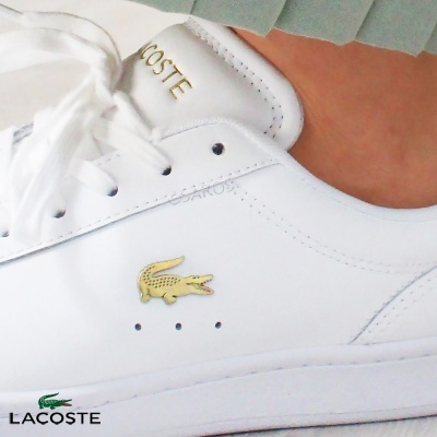 Tênis branco Lacoste em pele com crocodilo dourado e atacadores brancos