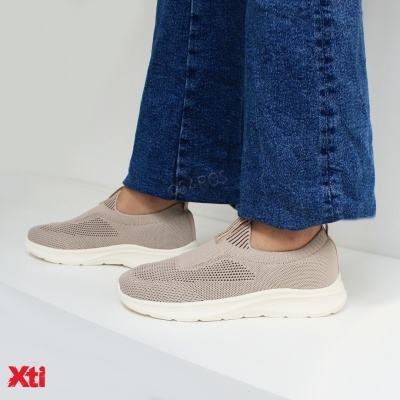 Ténis slip-on bege com sola branca e calças de ganga azuis