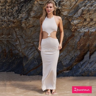 Vestido longo creme claro com recortes laterais em praia rochosa