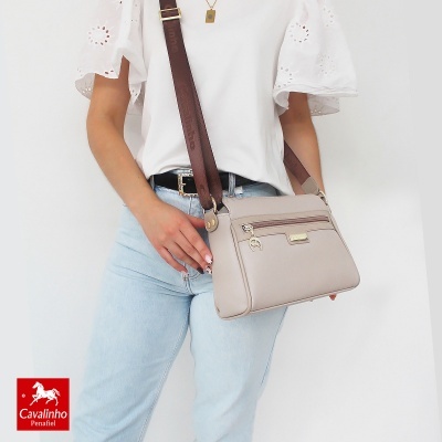 Mala cruzada bege com detalhes castanhos usada por pessoa com camisa branca e calças de ganga claras