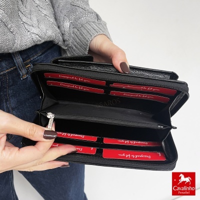 Carteira preta em pele com fecho de correr aberta com cartões vermelhos e várias divisórias