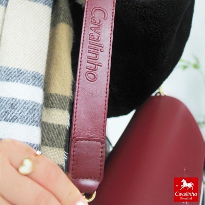 Alça de bolso em pele vermelha com logo Cavalinho, lenço xadrez e mão com anel