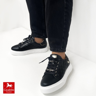 Ténis pretos com sola branca e detalhes em dourado e pedras brilhantes