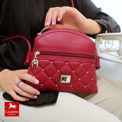 Mala vermelha em pele com padrão matelassé e detalhes metálicos dourados