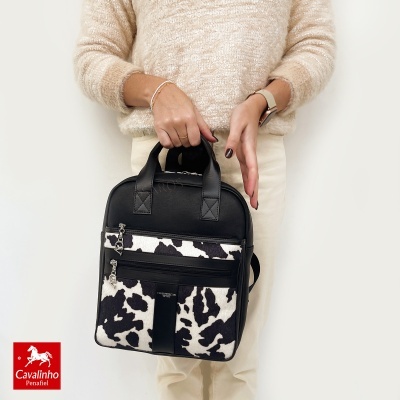 Mochila preta com padrão animal preto e branco segurada por pessoa