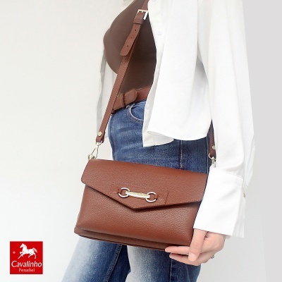 Mala de ombro feminina em pele castanha com fecho metálico prateado em outfit casual