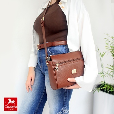 Mala castanha em pele com cinto castanho, destacada em look casual com jeans e camisa branca