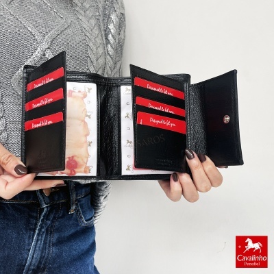 Carteira preta de couro com cartões vermelhos e bolsas transparentes segurada por mãos.