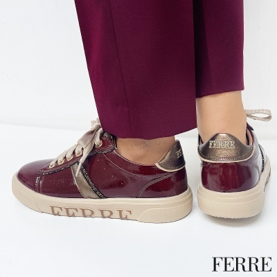 Sapatos desportivos vermelhos brilhantes com detalhes dourados e sola bege com marca FERRE.