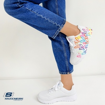 Ténis brancos Skechers com corações coloridos ao lado e calças de ganga azuis