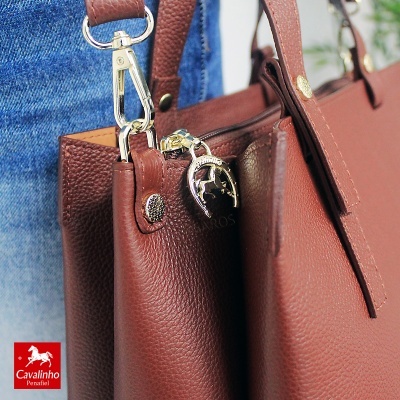 Mala castanha em pele com textura granulada e puxador metálico dourado em forma de ferradura