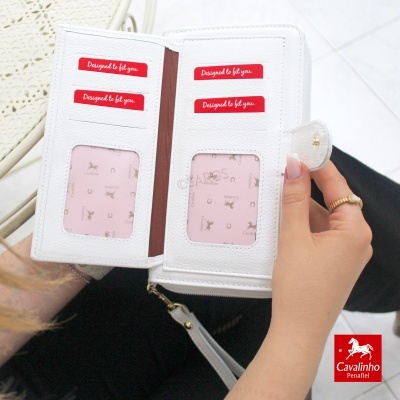 Carteira branca com etiquetas vermelhas e interior rosa com padrões, em mão feminina