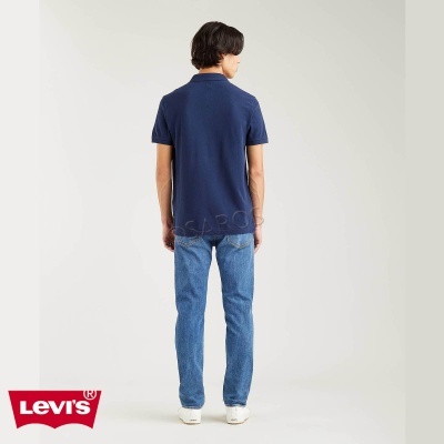 Pessoa de costas com polo azul escuro e calças de ganga azuis