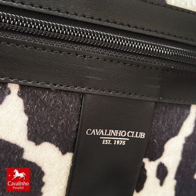 Bolsa com peluche preto e branco e detalhes em pele preta com fecho de correr.