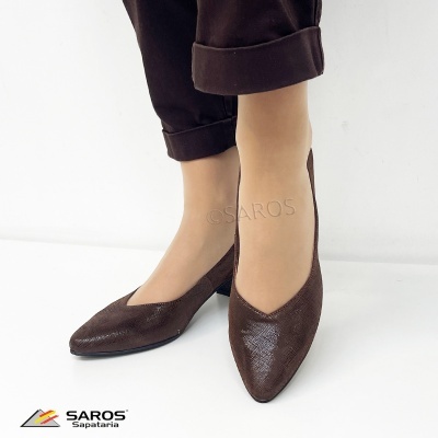 Sapatos de salto baixo castanhos com textura fina usados com calças castanhas em fundo branco