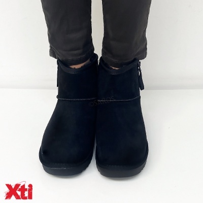 Botas pretas curtas em camurça com solado preto, usadas com calças pretas, imagem em fundo branco e logótipo vermelho Xti.