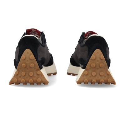 Ténis pretos e castanhos vistos de trás com sola castanha bolbosa e detalhe vermelho na lingueta