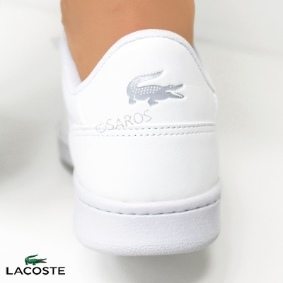 Traseira de sapatilha branca com logo crocodilo prateado e texto SAROS