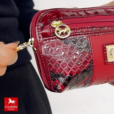 Bolsa vermelha com textura brilhante e puxador dourado com cavalo