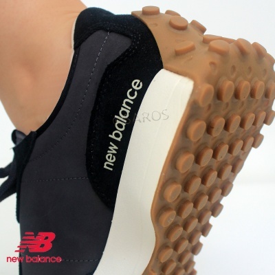 Sapatilha New Balance preta com sola branca e sola de borracha cor de caramelo com relevos circulares.