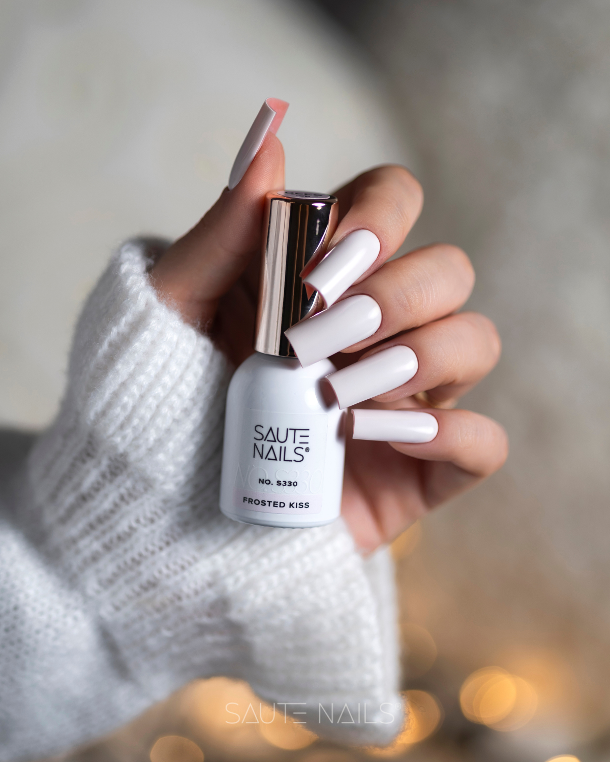 Verniz Gel S330 - Frosted Kiss (Rosa Leitoso Opaco) Frasco de verniz de unhas branco e unhas esmaltadas de branco com manga branca tricotada