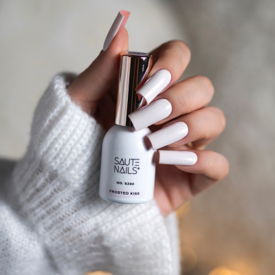 Frasco de verniz de unhas branco e unhas esmaltadas de branco com manga branca tricotada