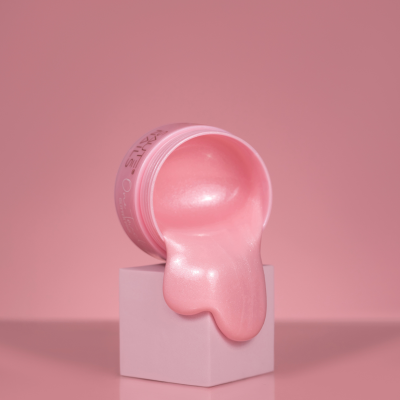 Recipiente rosa com creme a derramar sobre cubo cor-de-rosa