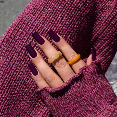 Mãos com unhas roxas e anéis em malha roxa