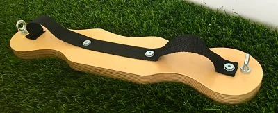 Prancha de madeira clara com correia preta ajustável e parafusos metálicos sobre relva artificial