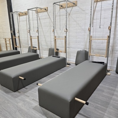 Conjunto de camas de Pilates com estrutura metálica, correntes e alças de madeira.