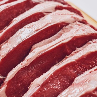 Fatias de carne crua vermelha com gordura sobre tábua de madeira