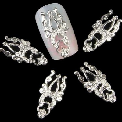 Peças prateadas decorativas de unha sobre fundo preto, uma aplicada numa unha artificial