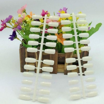 Mostruário de unhas artificiais brancas com flores coloridas ao fundo