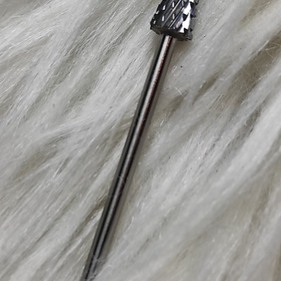 Broca cónica e texturada em metal sobre tecido branco felpudo